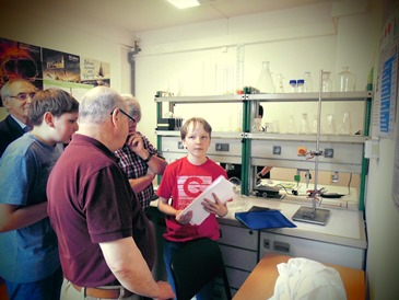 Zu sehen ist ein Schüler, der seine Arbeit in einem Labor präsentiert.